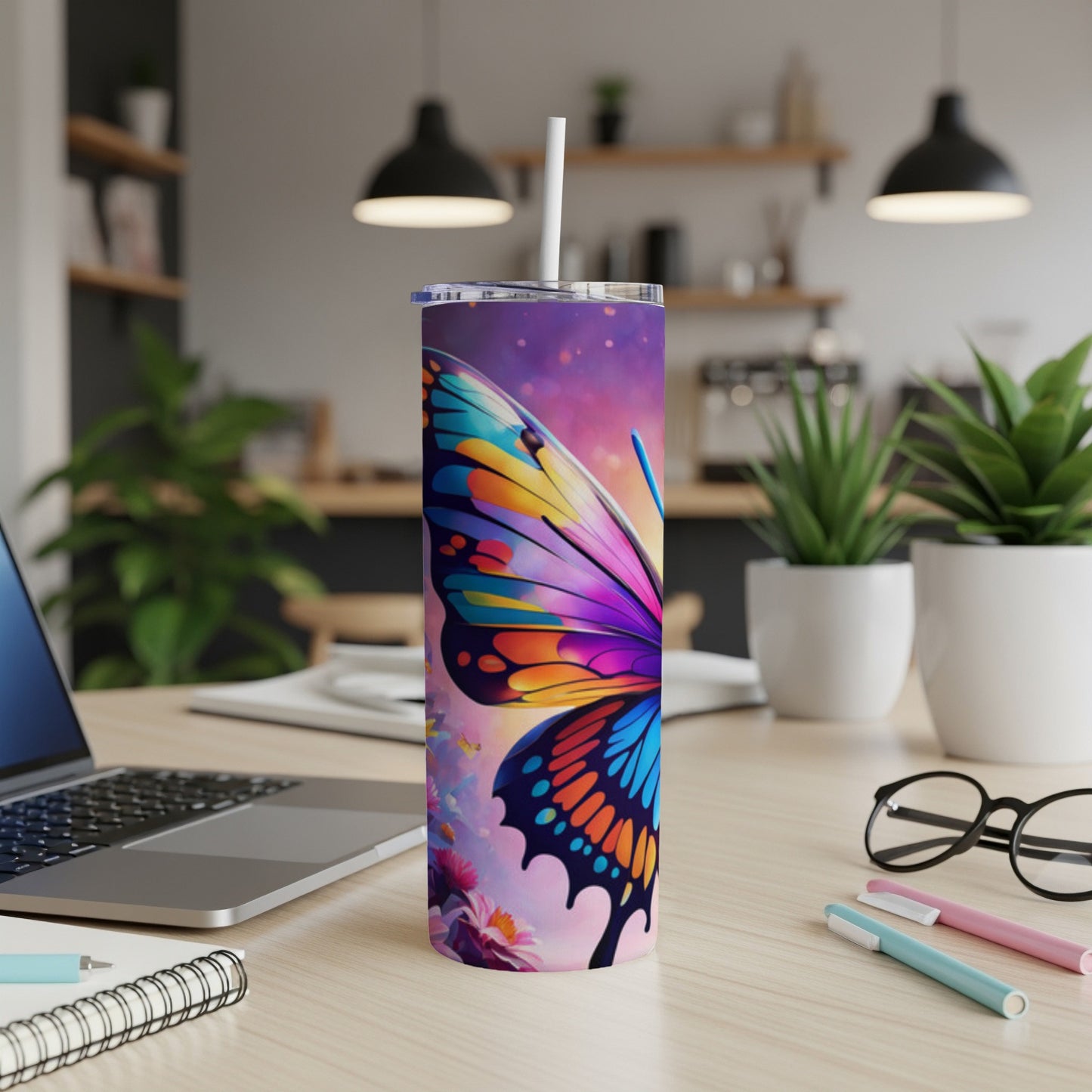 Tall tumbler with colorful butterfly design on desk next to laptop.