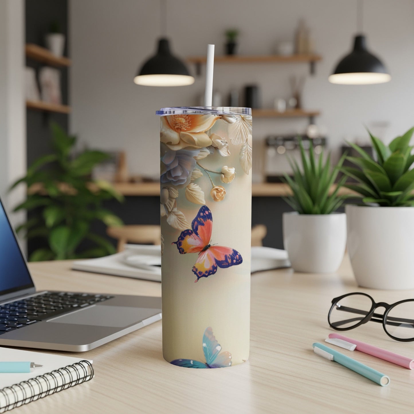 Tall tumbler with butterflies and floral accents on a desk.