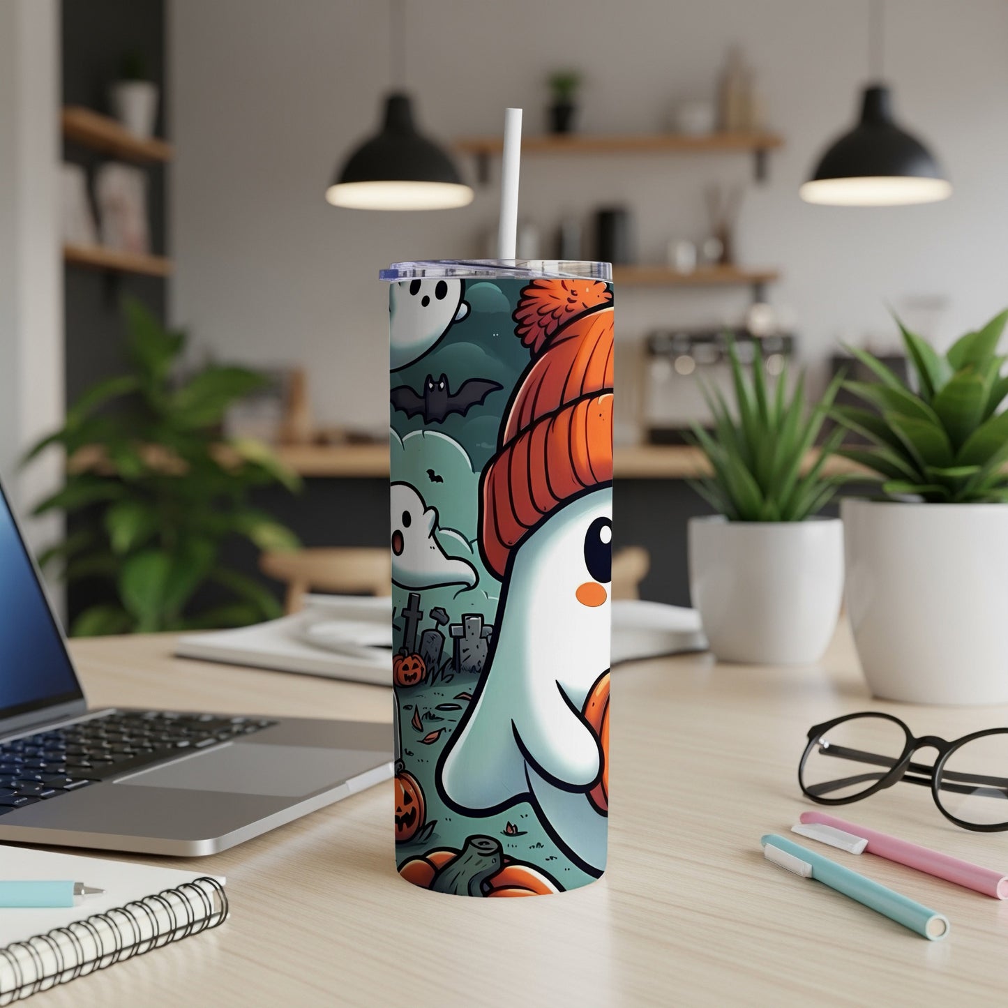 Tumbler with cartoon ghosts, bats, pumpkins, and gravestones on a Halloween-themed design.