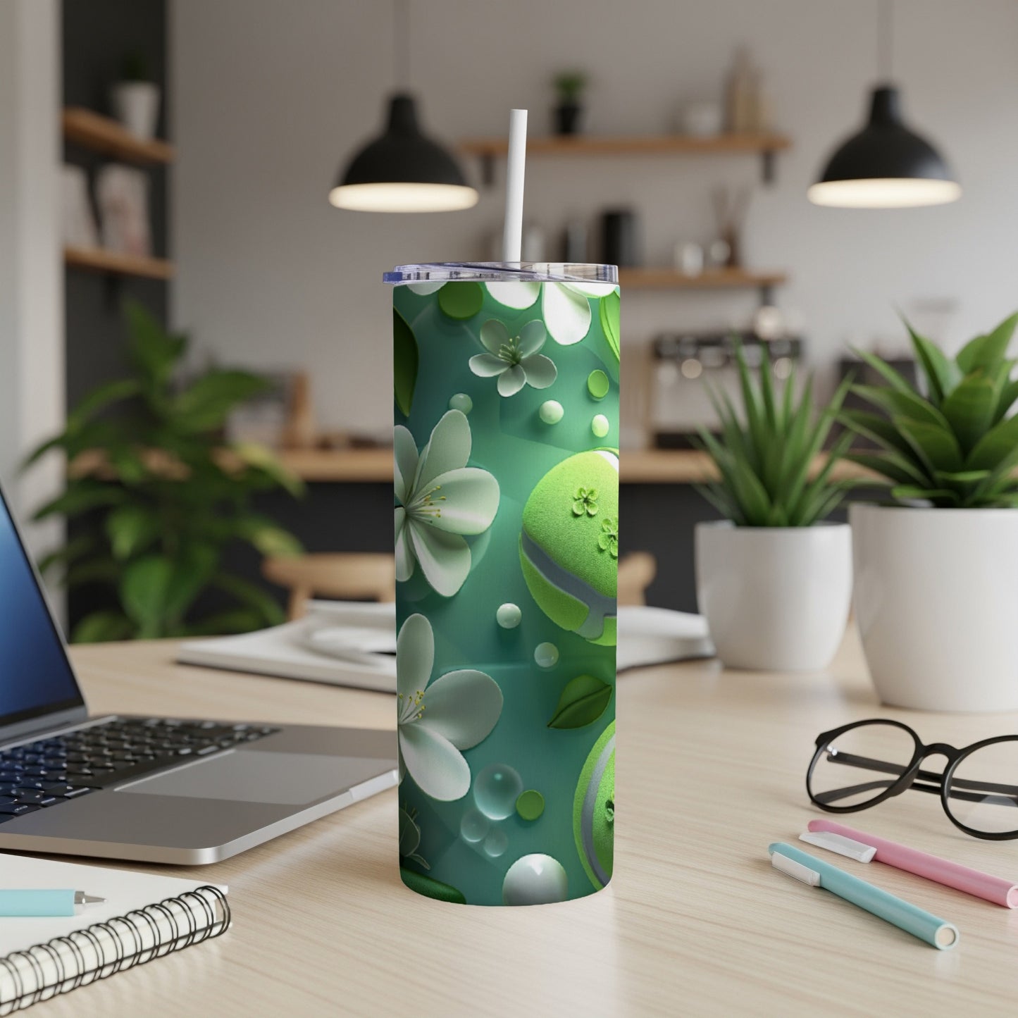 Green floral patterned tumbler with white straw on a desk.