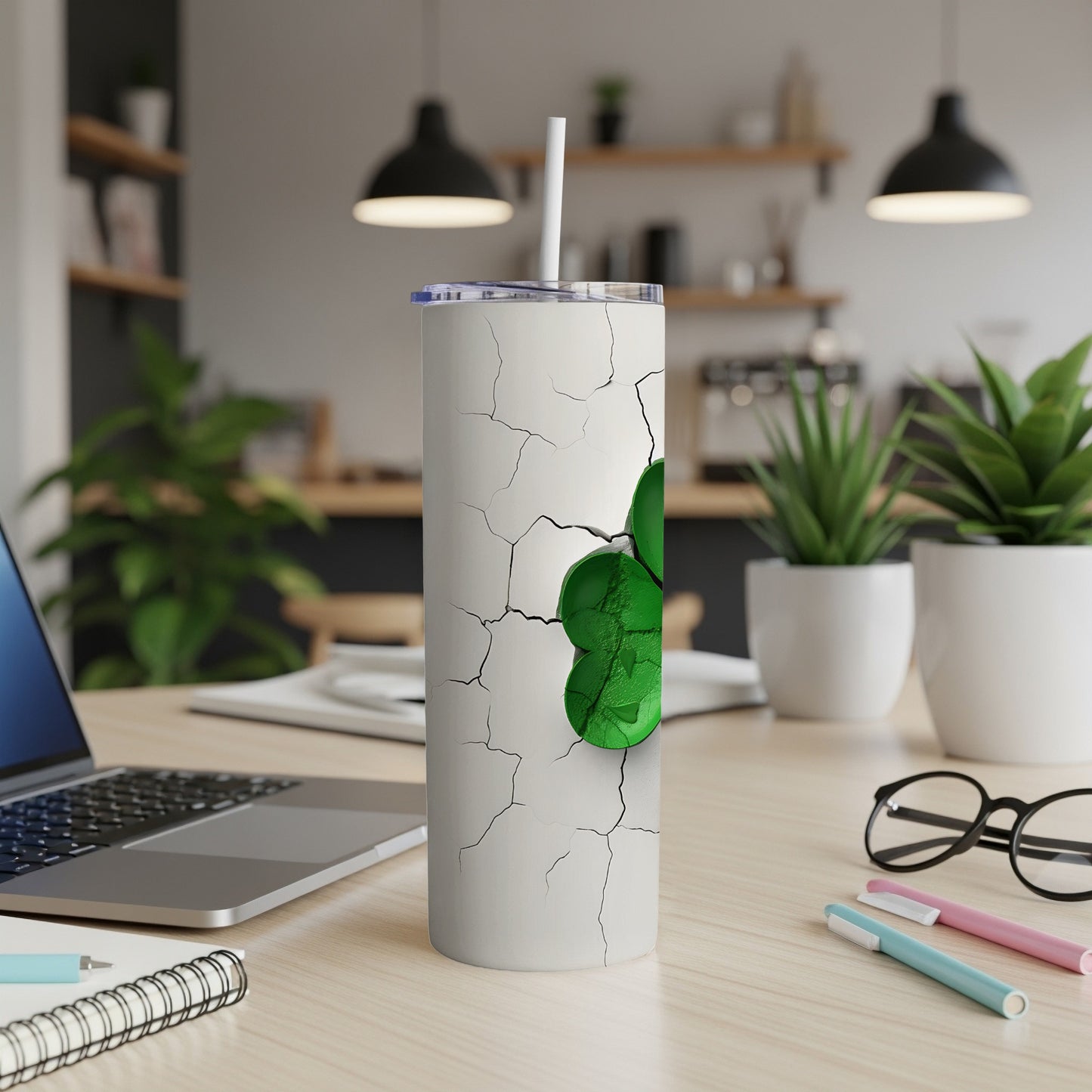White tumbler with cracked design and green shamrock, on a desk.