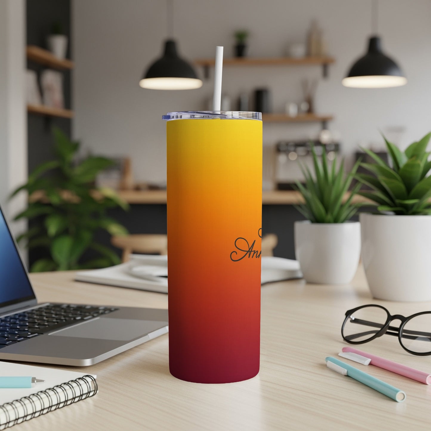 Sunset gradient tumbler with "An" inscribed on it on a desk.