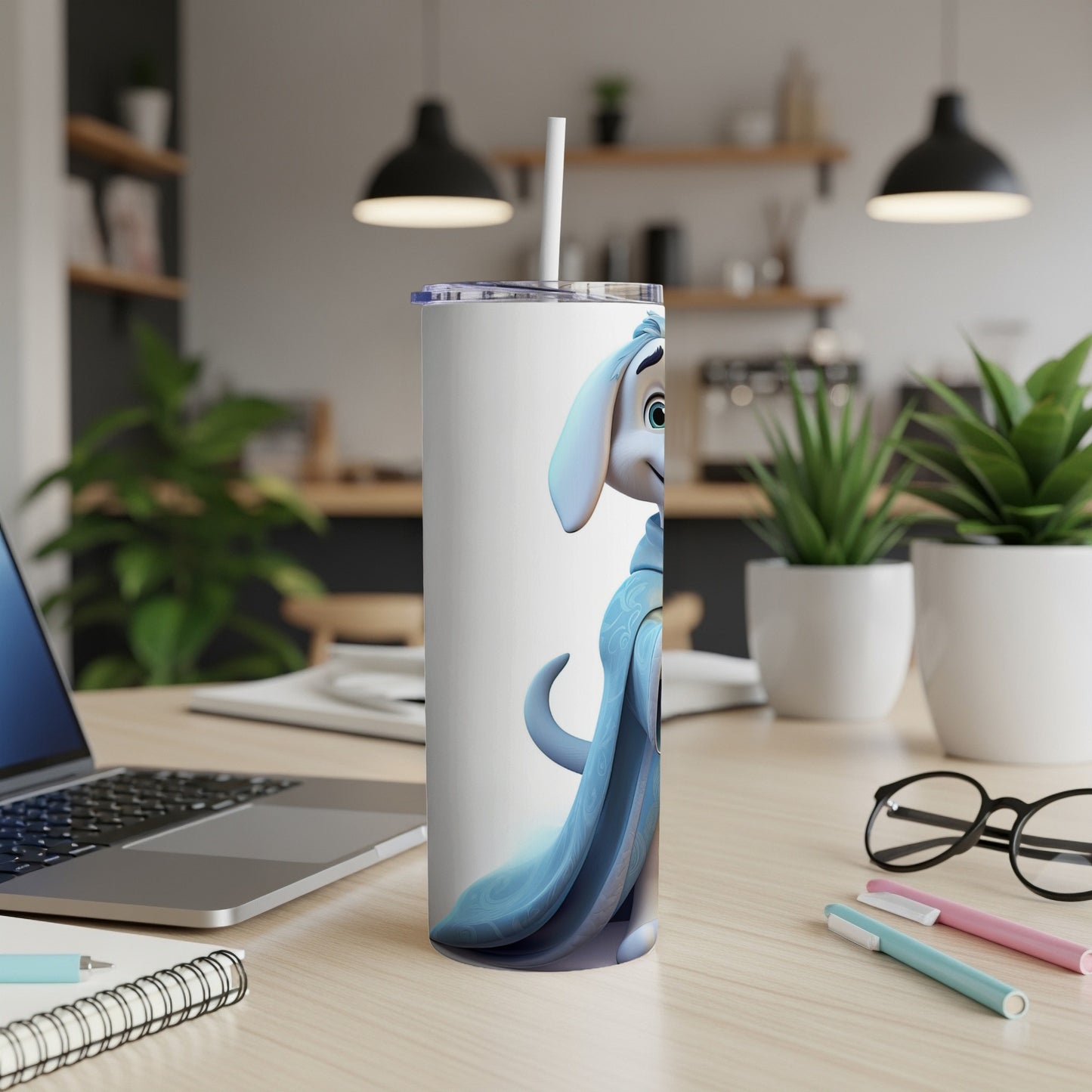 White tumbler with cartoon character and blue cloak, on a desk.