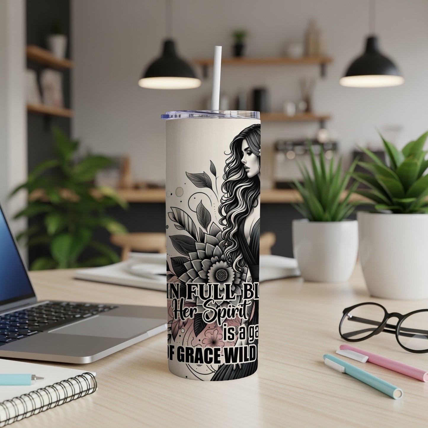 Tall tumbler with floral design and woman's profile, reads "In her full beauty is a garden of grace wild."