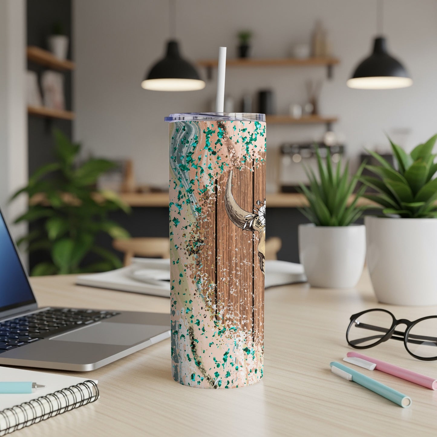 Wooden tumbler with abstract marbling and bull head design, on a desk.
