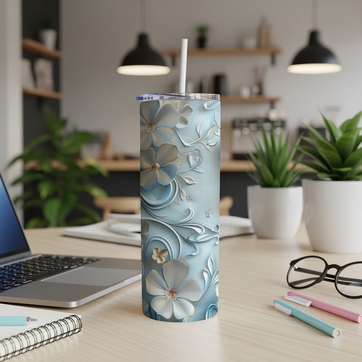 Blue floral embossed tumbler with a white straw on a desk.