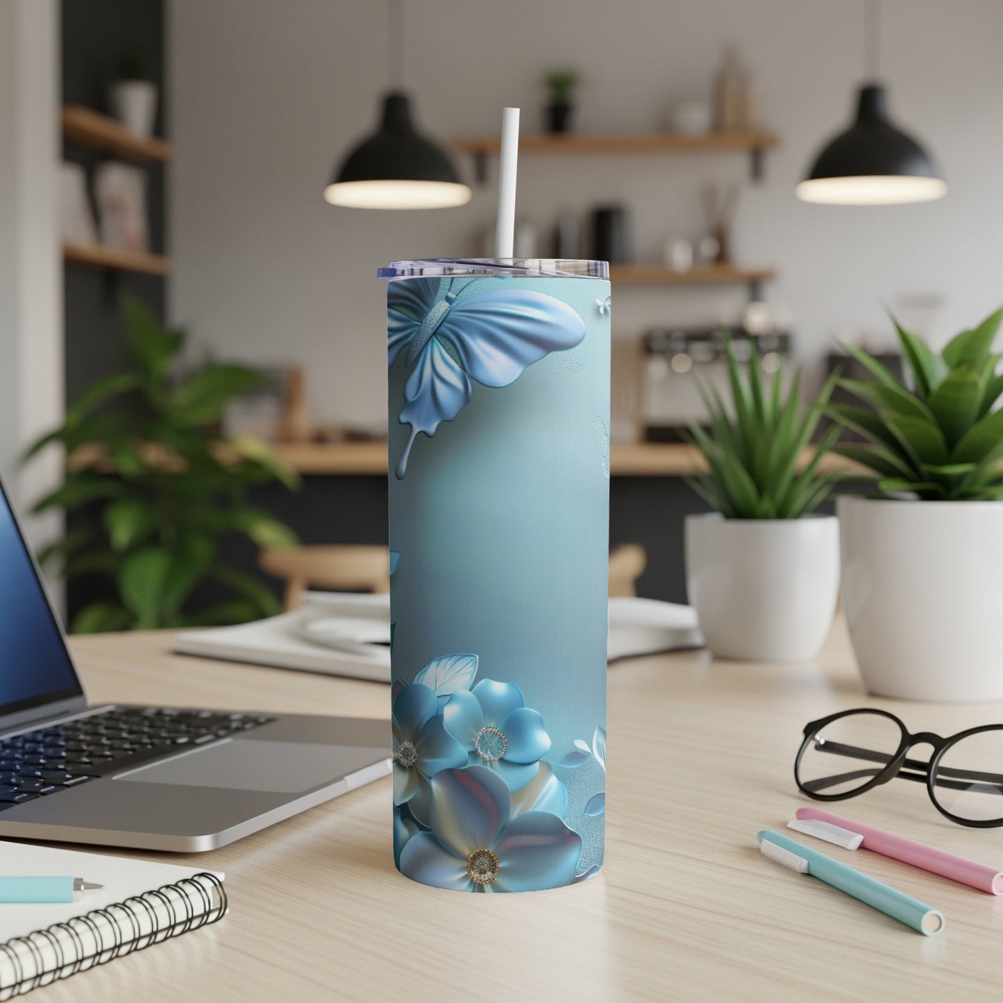 Blue floral tumbler with butterfly on a desk with laptop.