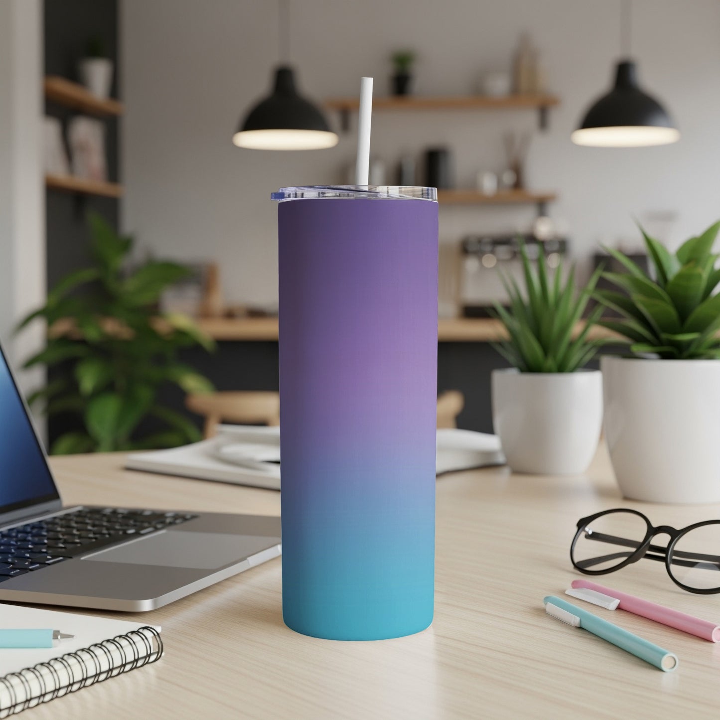 Gradient purple and turquoise tumbler with straw on desk.