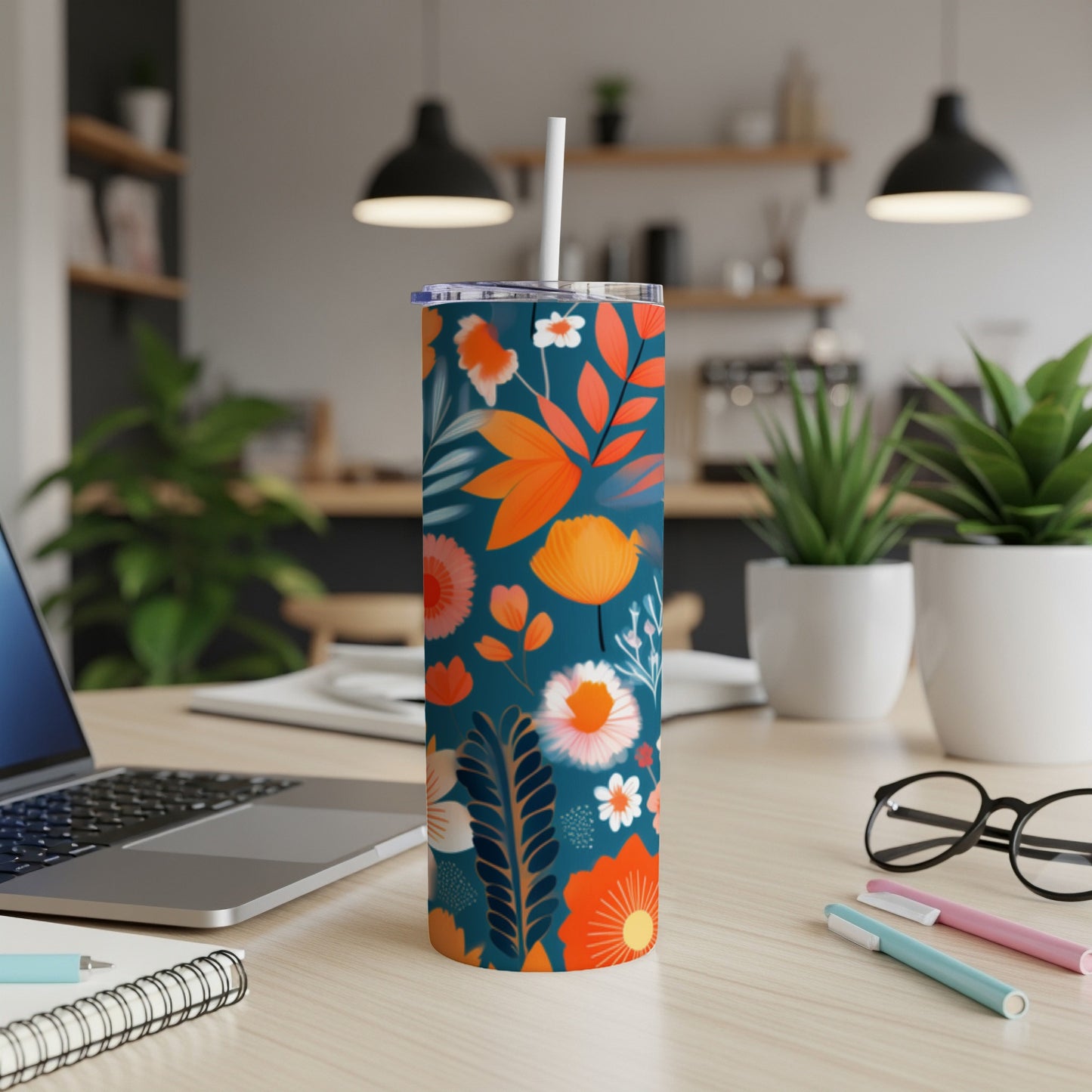 Tumbler with teal background and orange and white floral and leaf pattern.