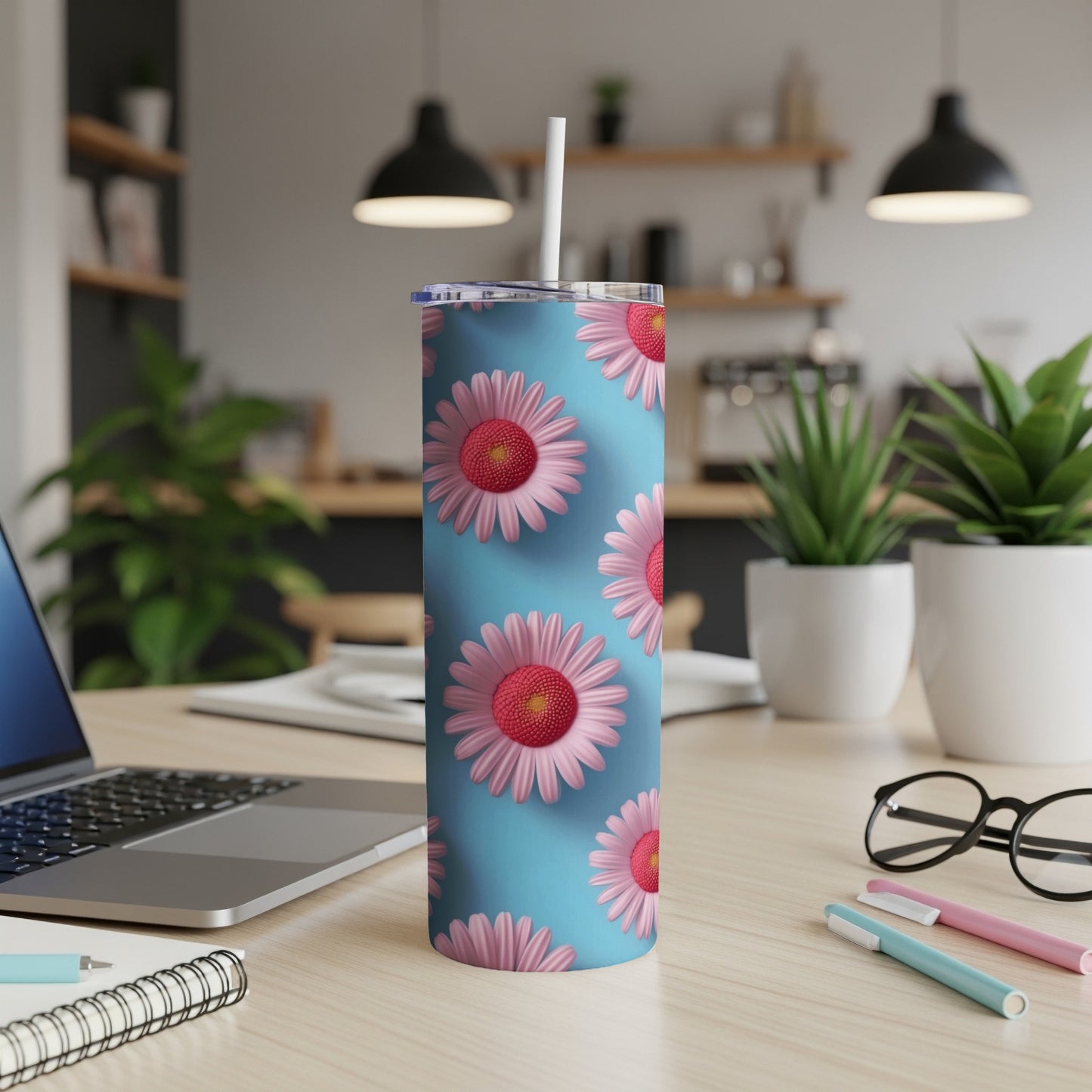 Blue tumbler with pink and red daisies, sitting on a desk.