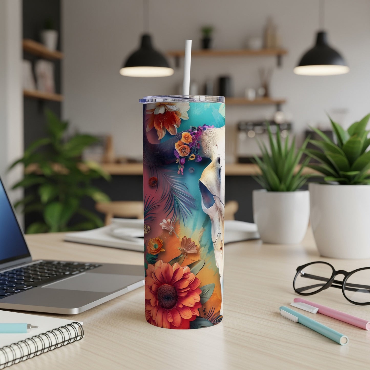 Floral skull tumbler with straw on a desk.
