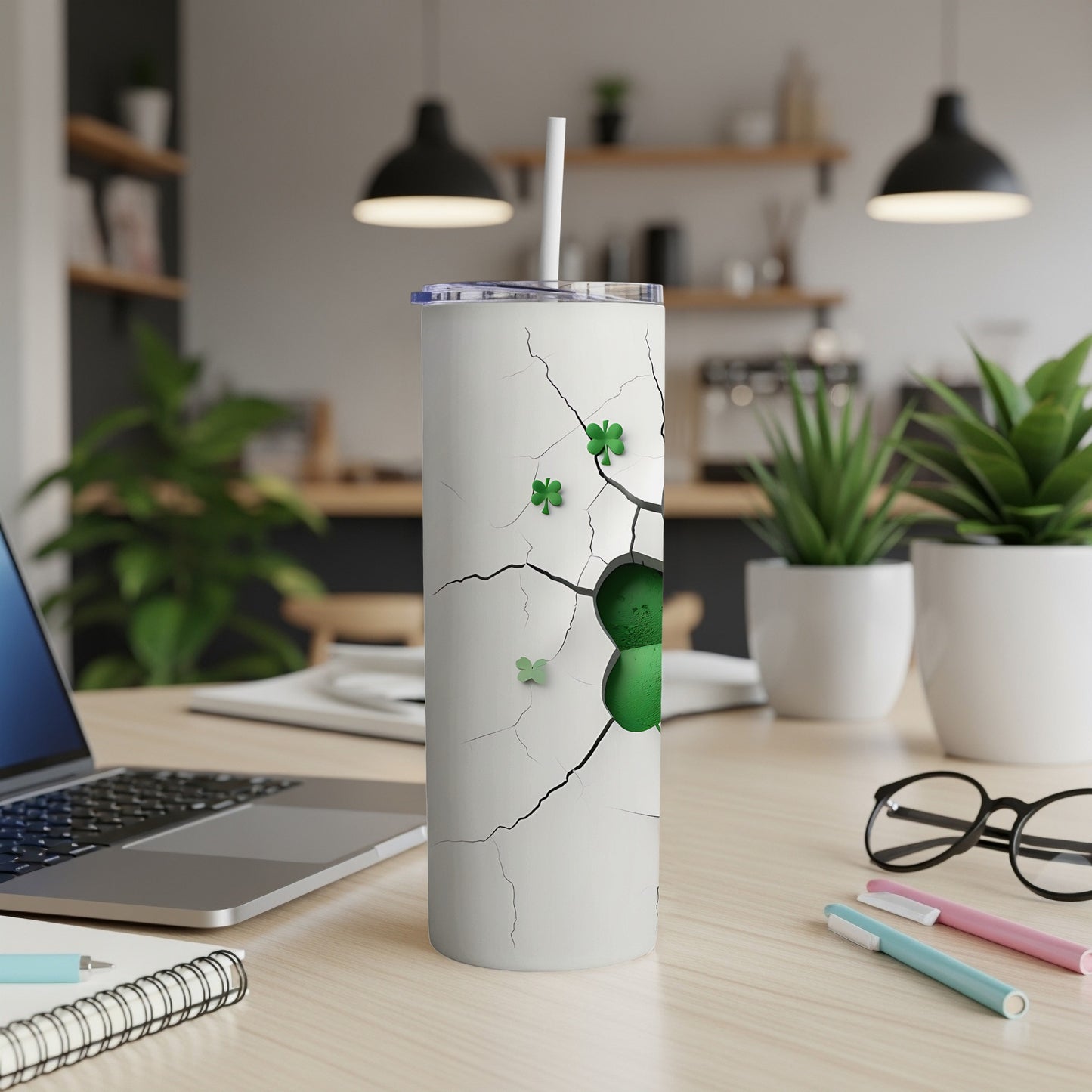 White tumbler with cracked pattern and green shamrocks, on a desk.
