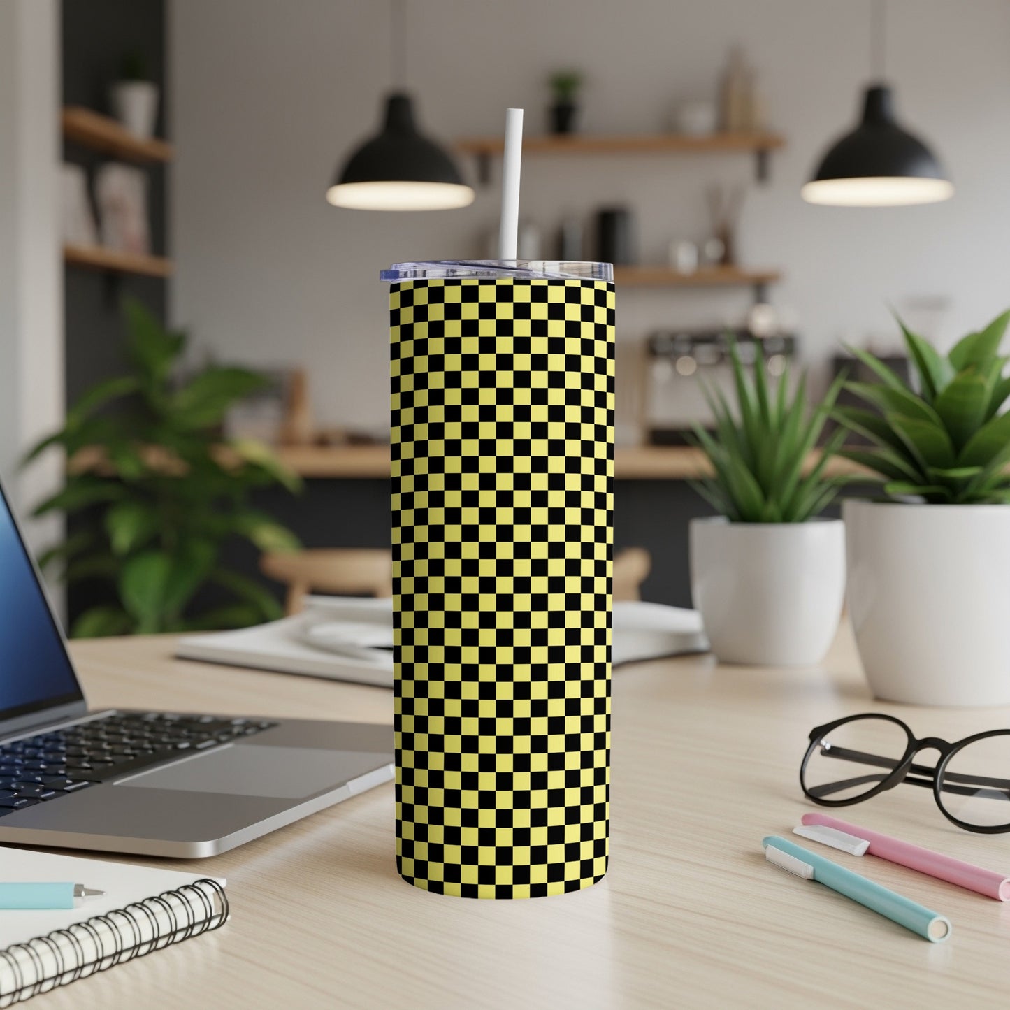Yellow and black checkered tumbler with white straw on desk.