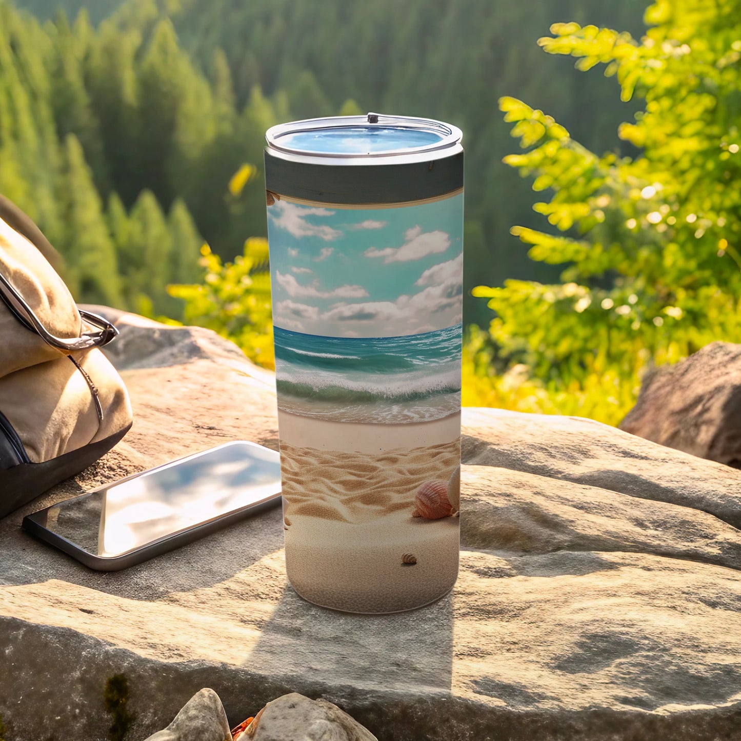 Tall tumbler with a beach scene and ocean waves, next to a phone.