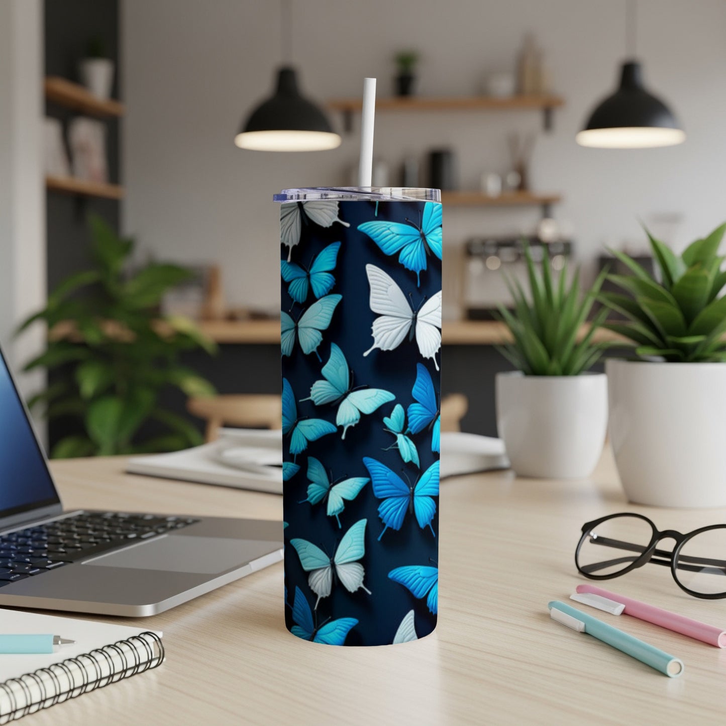 Blue and white butterflies on a dark background cover a skinny tumbler with a straw.