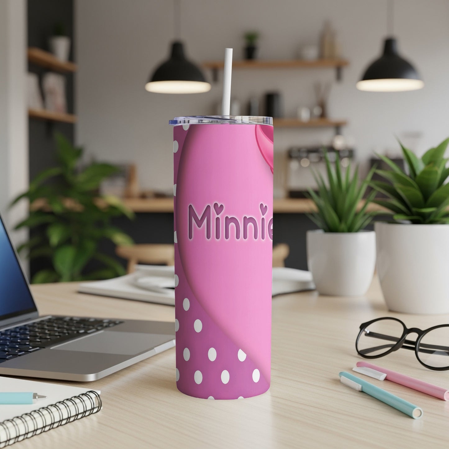 Pink tumbler with "Minnie" text and white polka dots on a desk.