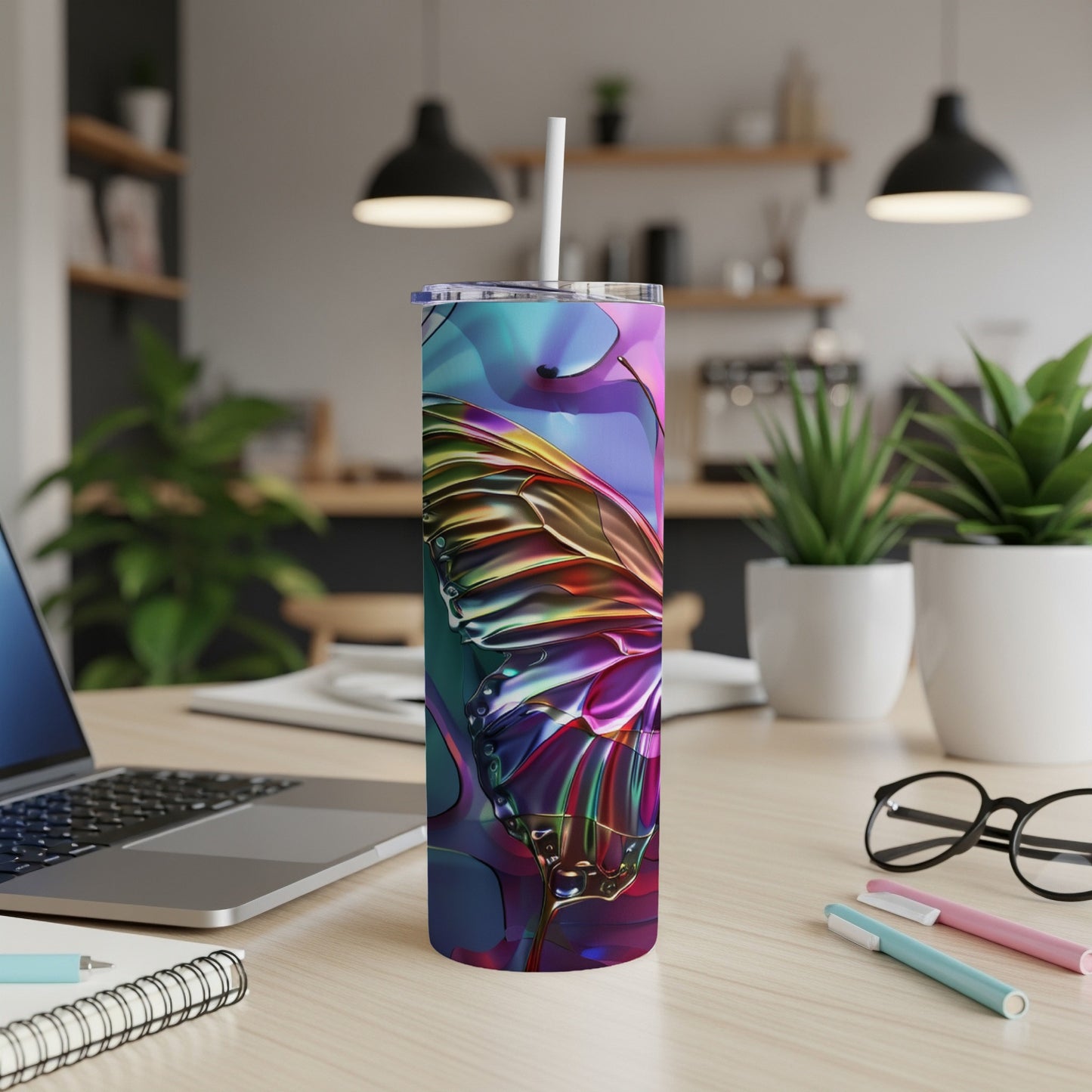 Colorful butterfly wing design on a white tumbler with straw on a desk.
