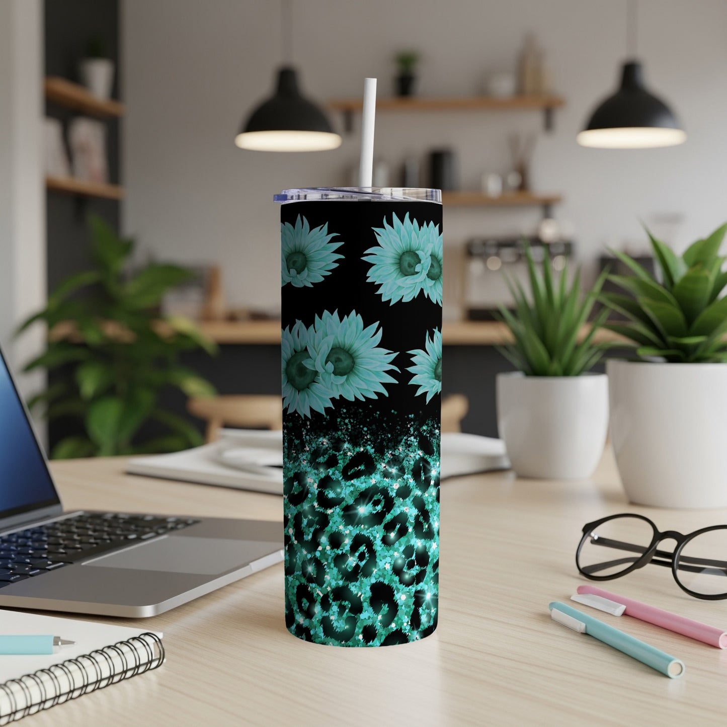 Teal glitter leopard print and sunflower tumbler with straw on desk.