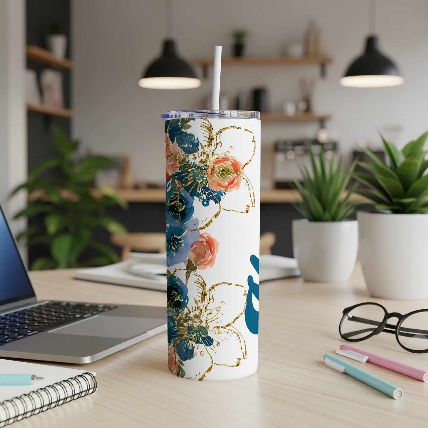White tumbler with floral design and white straw on desk.