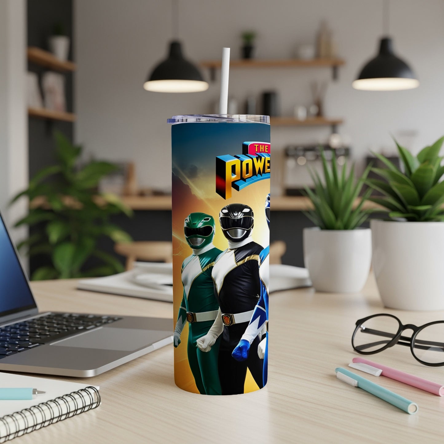 Power Rangers characters on a skinny tumbler with a laptop and office supplies.