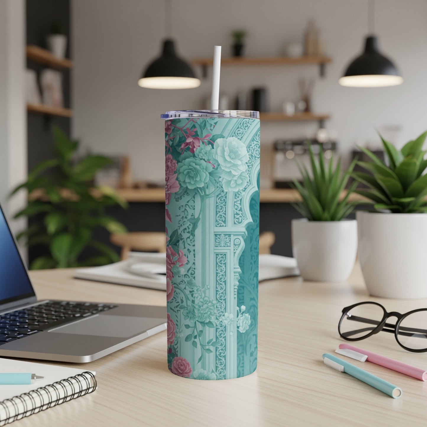 Turquoise tumbler with floral and architectural pattern and straw.