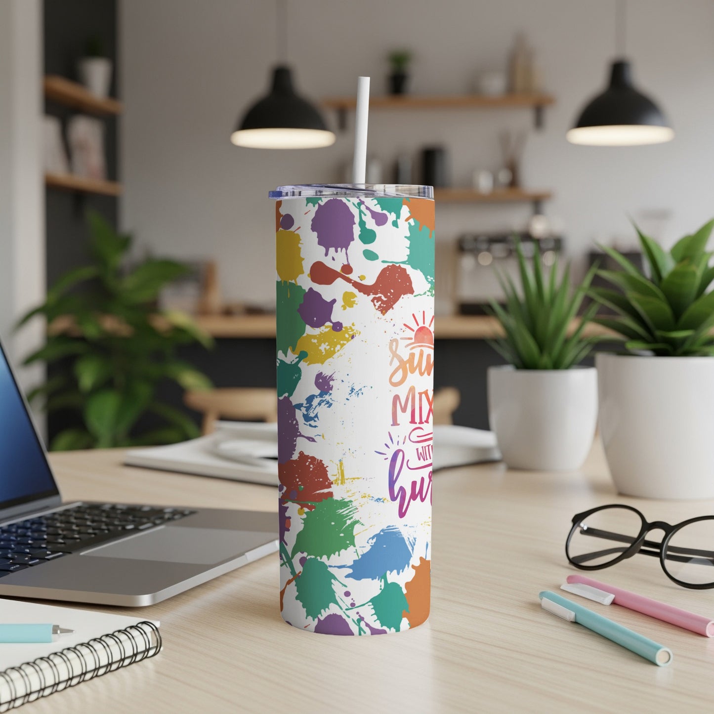 White tumbler with colorful paint splatters and text.