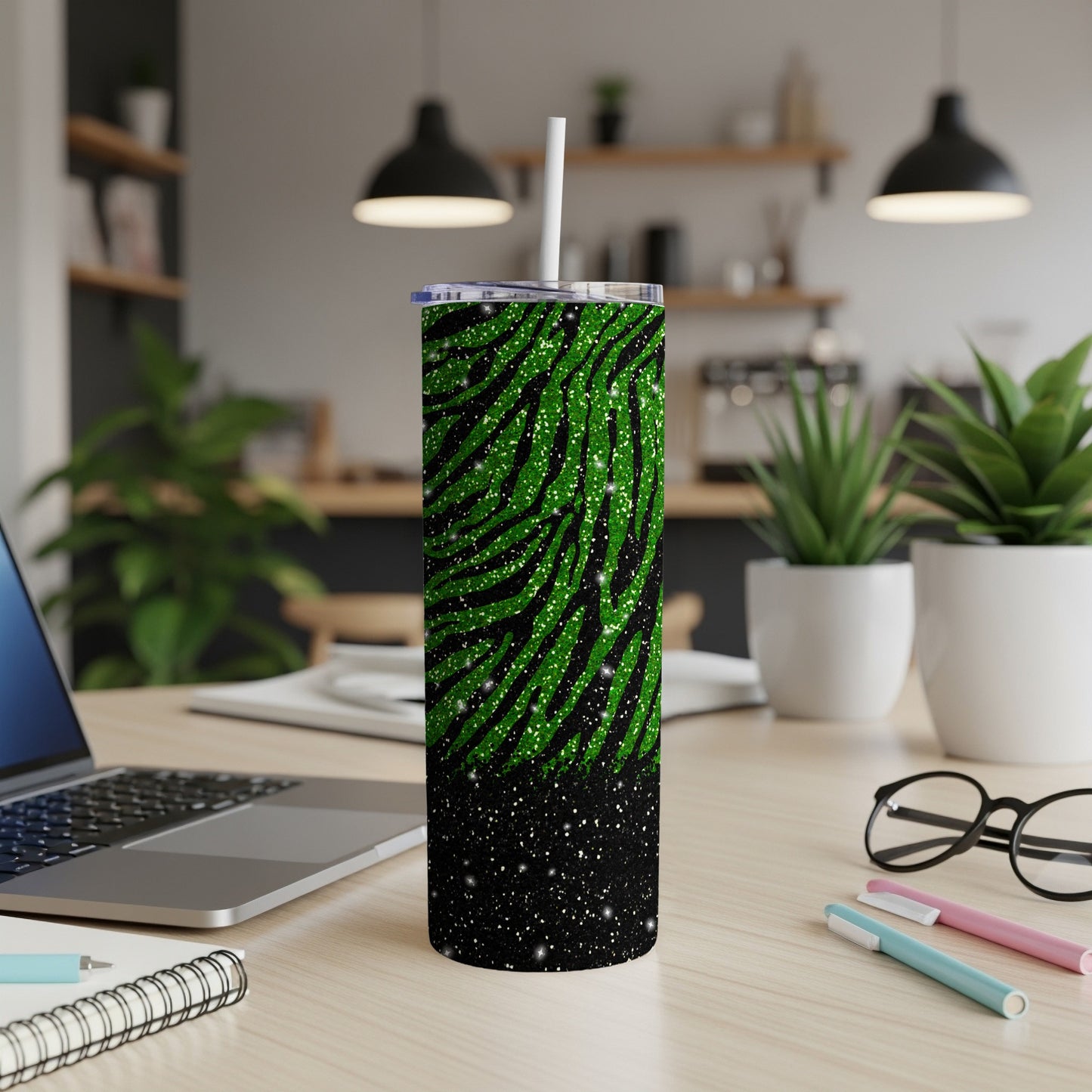 Black and green glitter zebra print tumbler with white straw, on a desk.