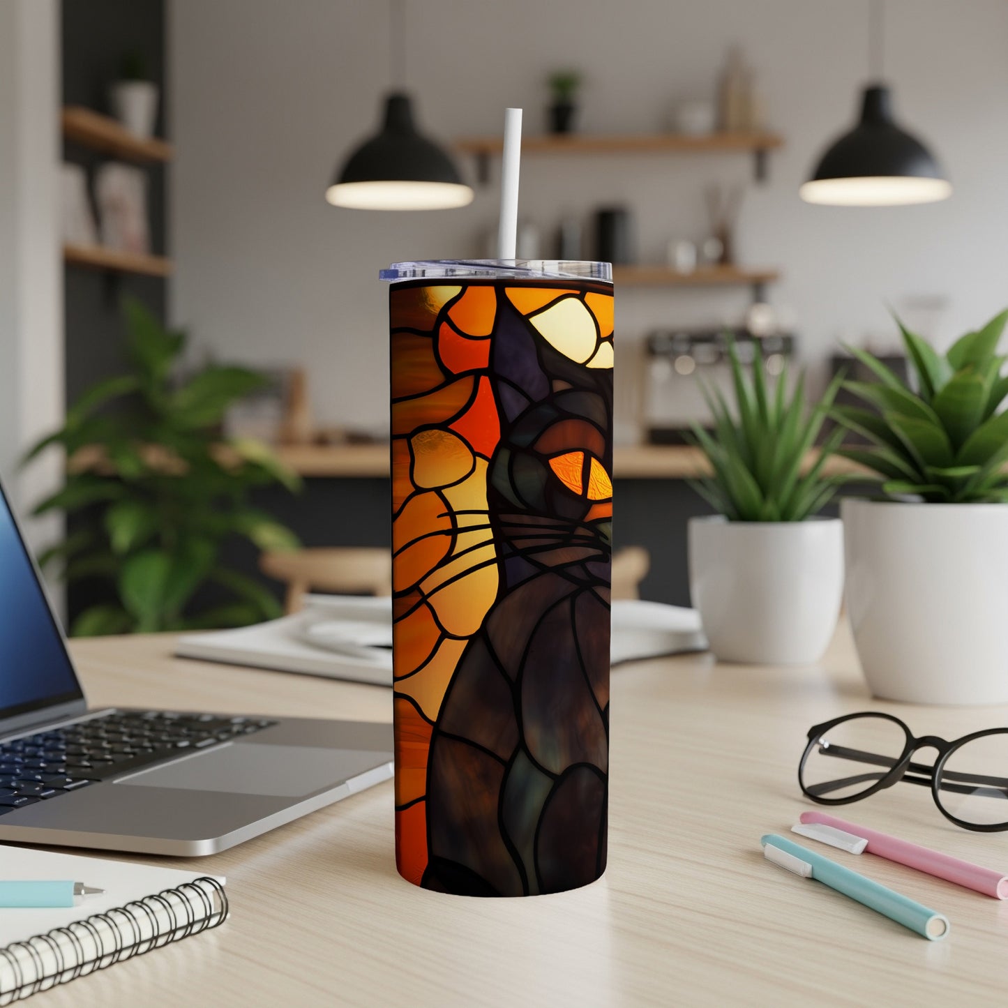 Stained glass cat tumbler with straw on a desk.