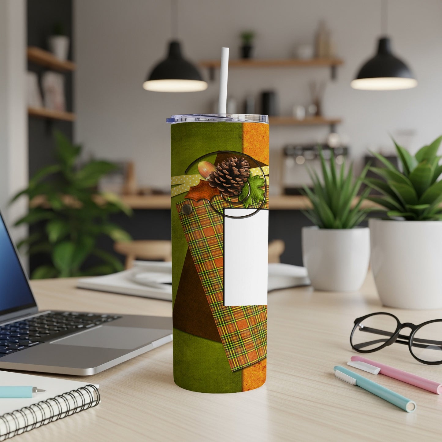 Patterned tumbler with plaid and fall leaves, on a desk.