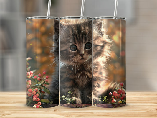 Fluffy kitten with large eyes sits among berries and plants.