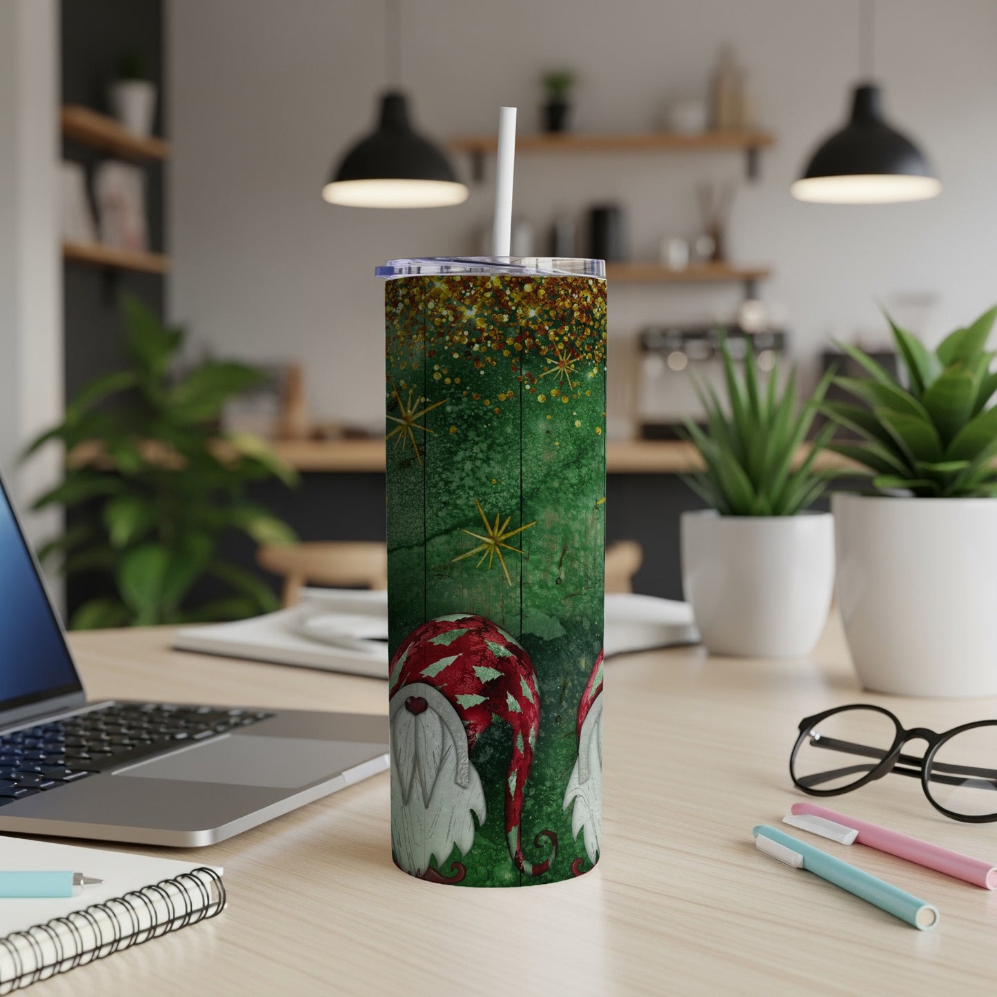 Green tumbler with glitter and two gnomes, placed on a desk.
