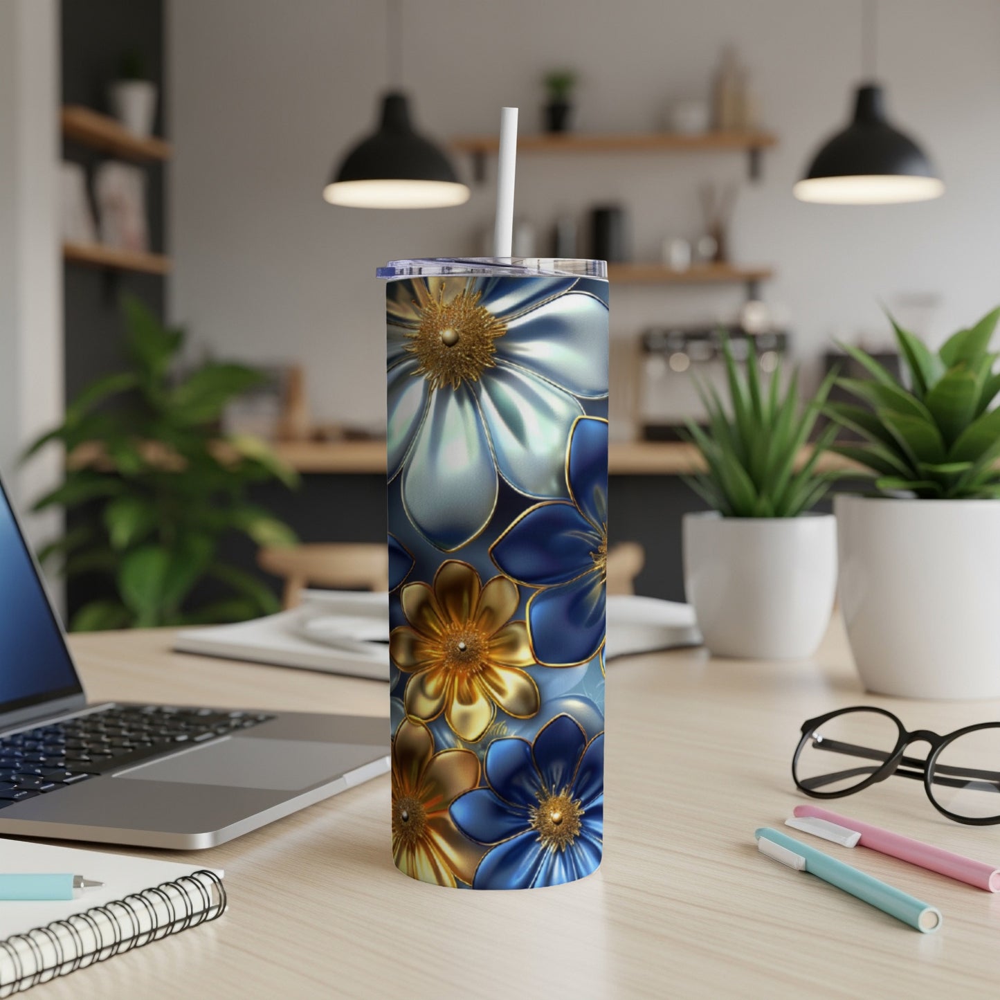 Blue, gold, and white floral tumbler on a desk with a laptop and pens.