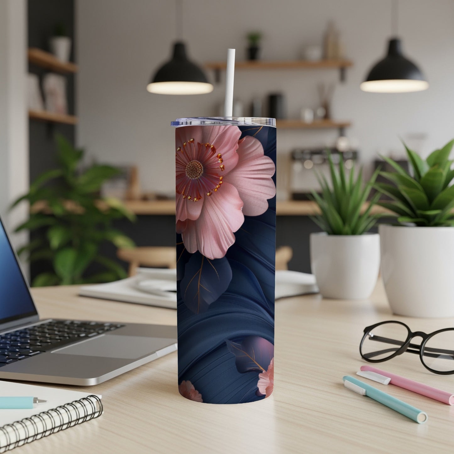 Floral tumbler with straw on a desk next to a laptop.
