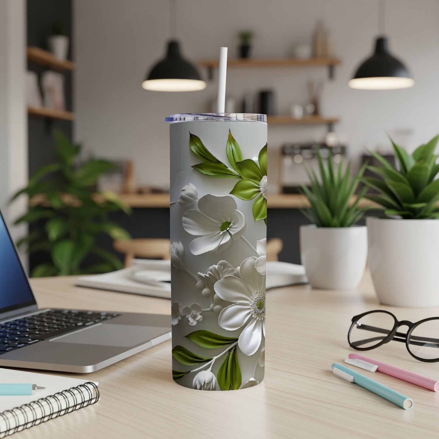 White floral patterned tumbler with straw on a desk.