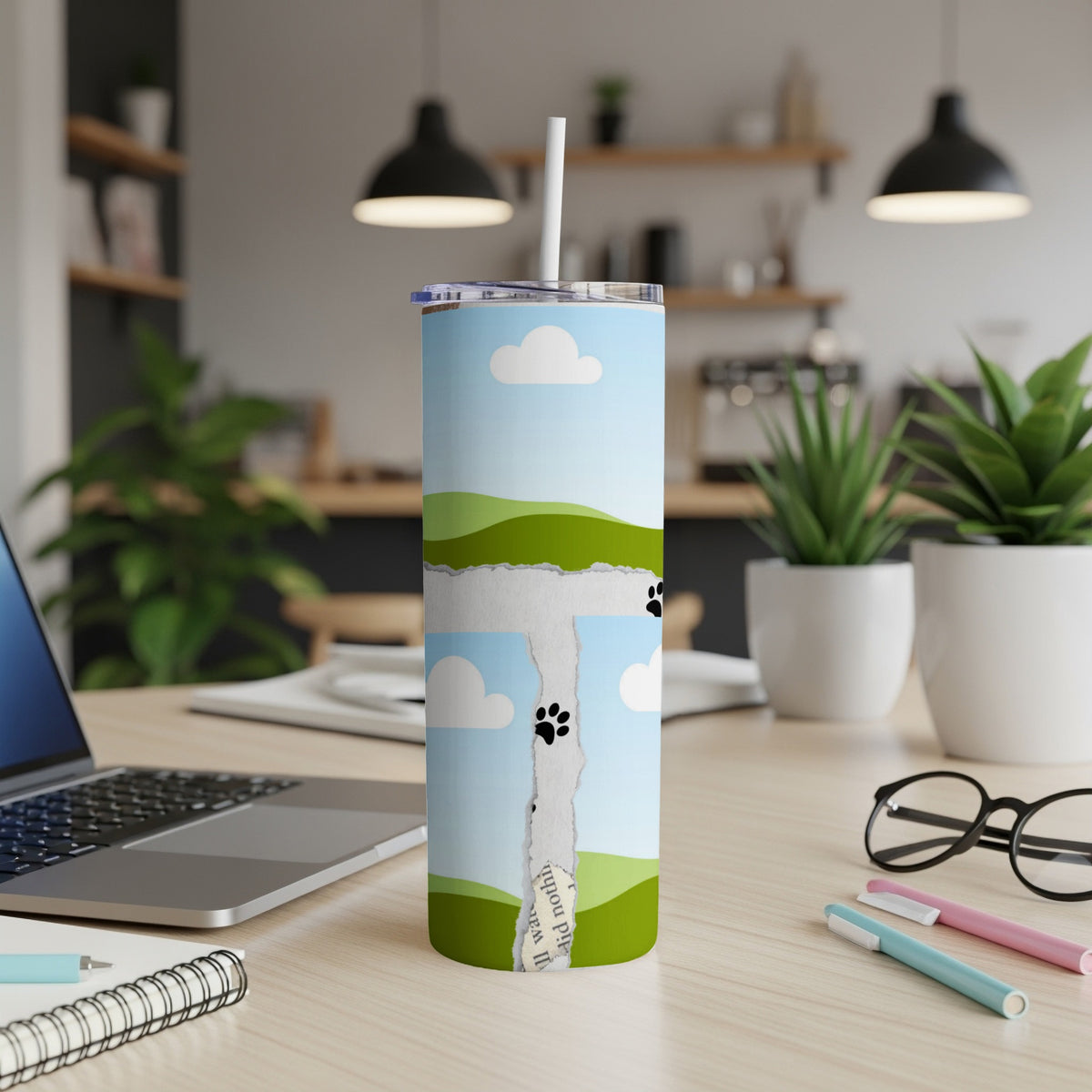 Tumbler with torn paper design showing clouds, hills, and paw prints.