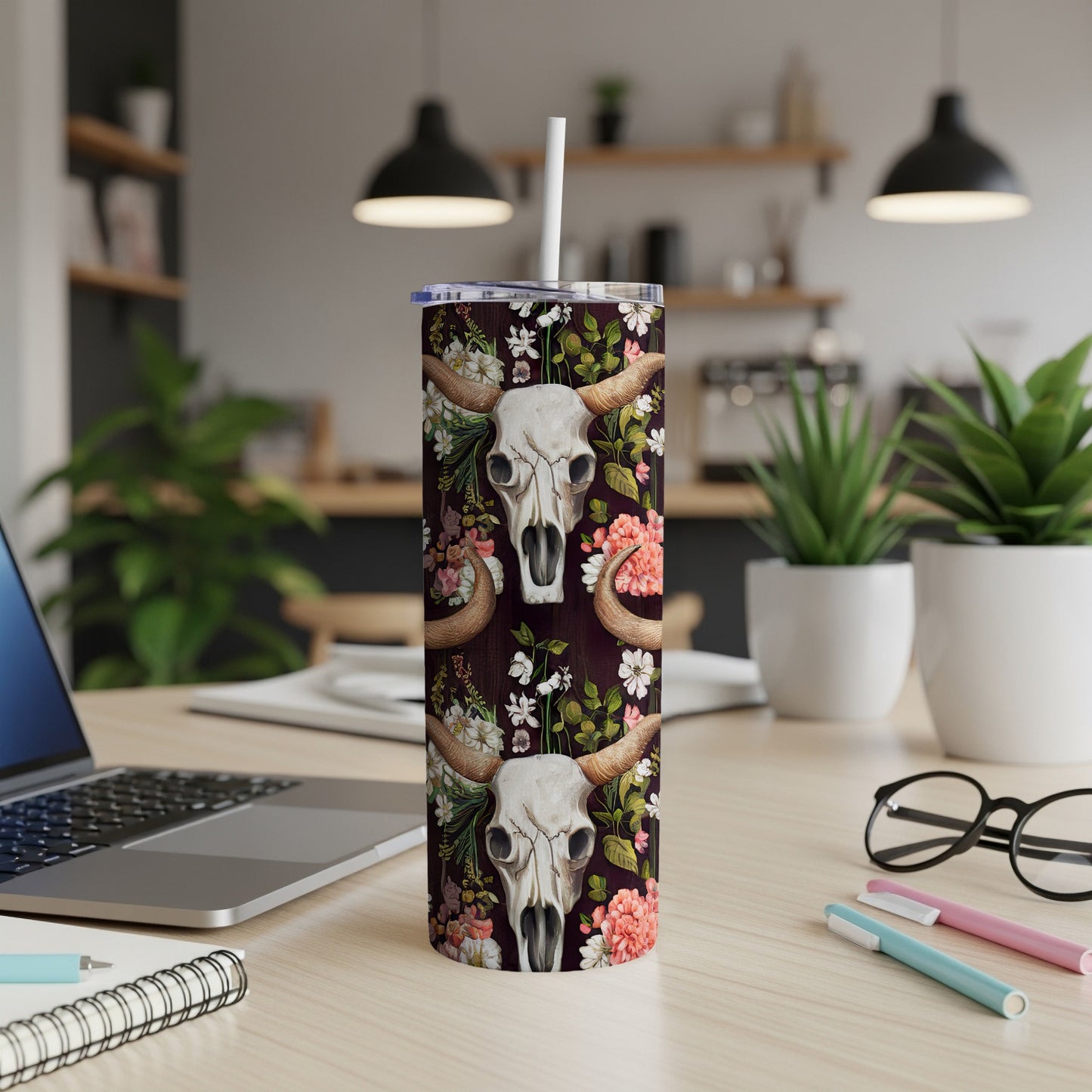 Cow skull with floral details on a dark background, on a tumbler.