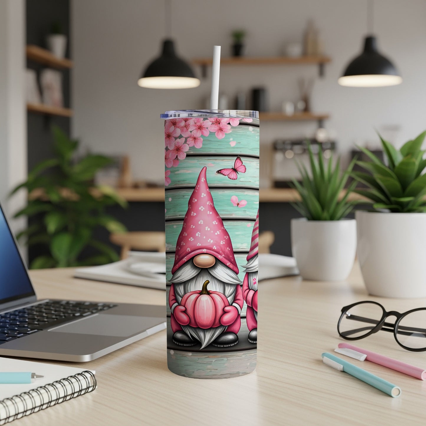 Two gnomes with pink hats and pumpkins on a teal wood background.