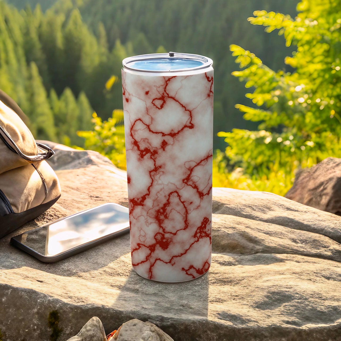Marble pattern tumbler with red veins on outdoor table with phone and bag.