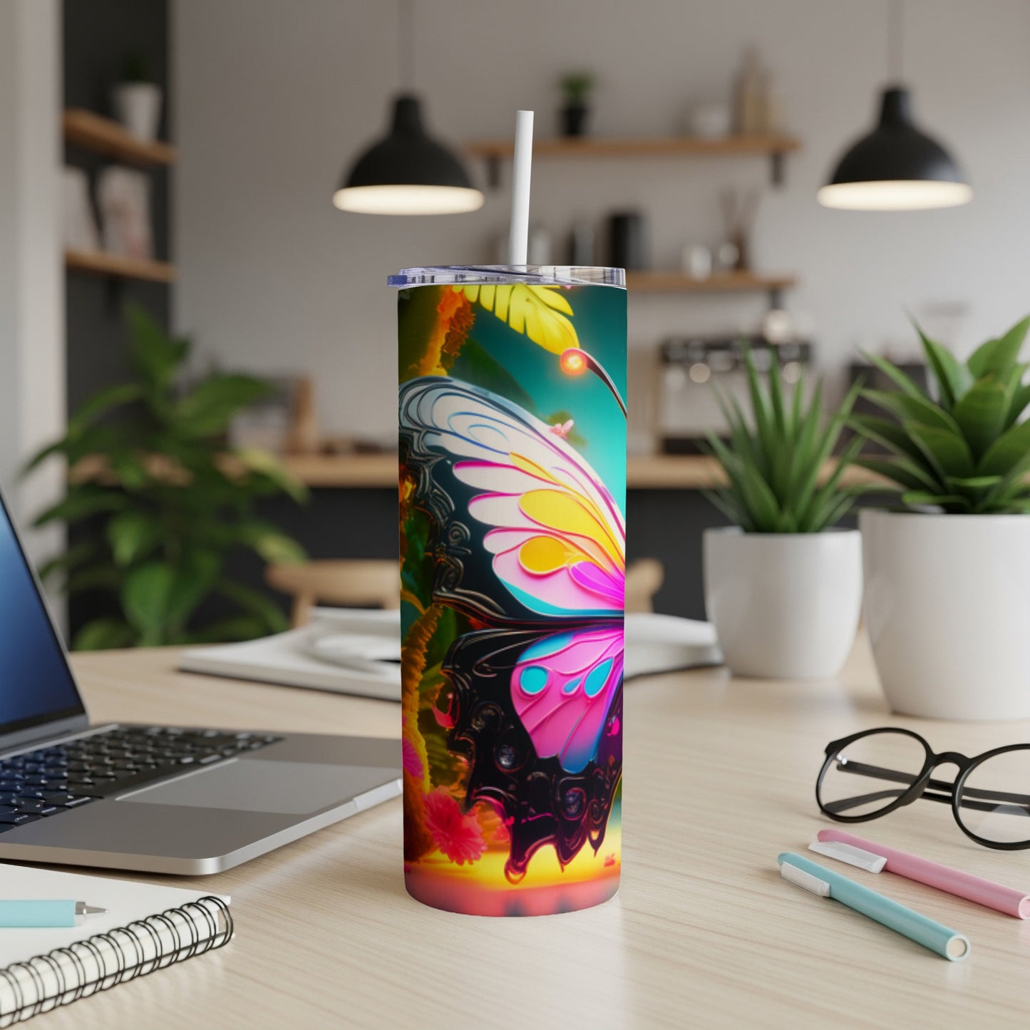 Tumbler with a vibrant butterfly design and a straw on a desk.