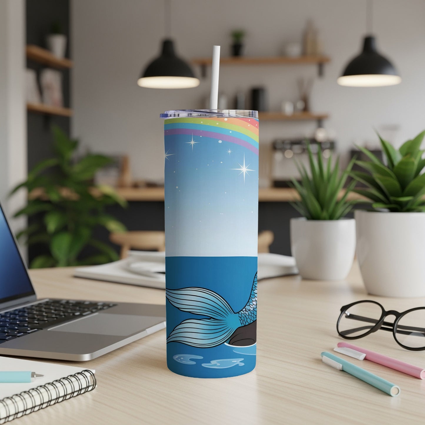 Tall tumbler with mermaid tail, rainbow, and stars on a desk.