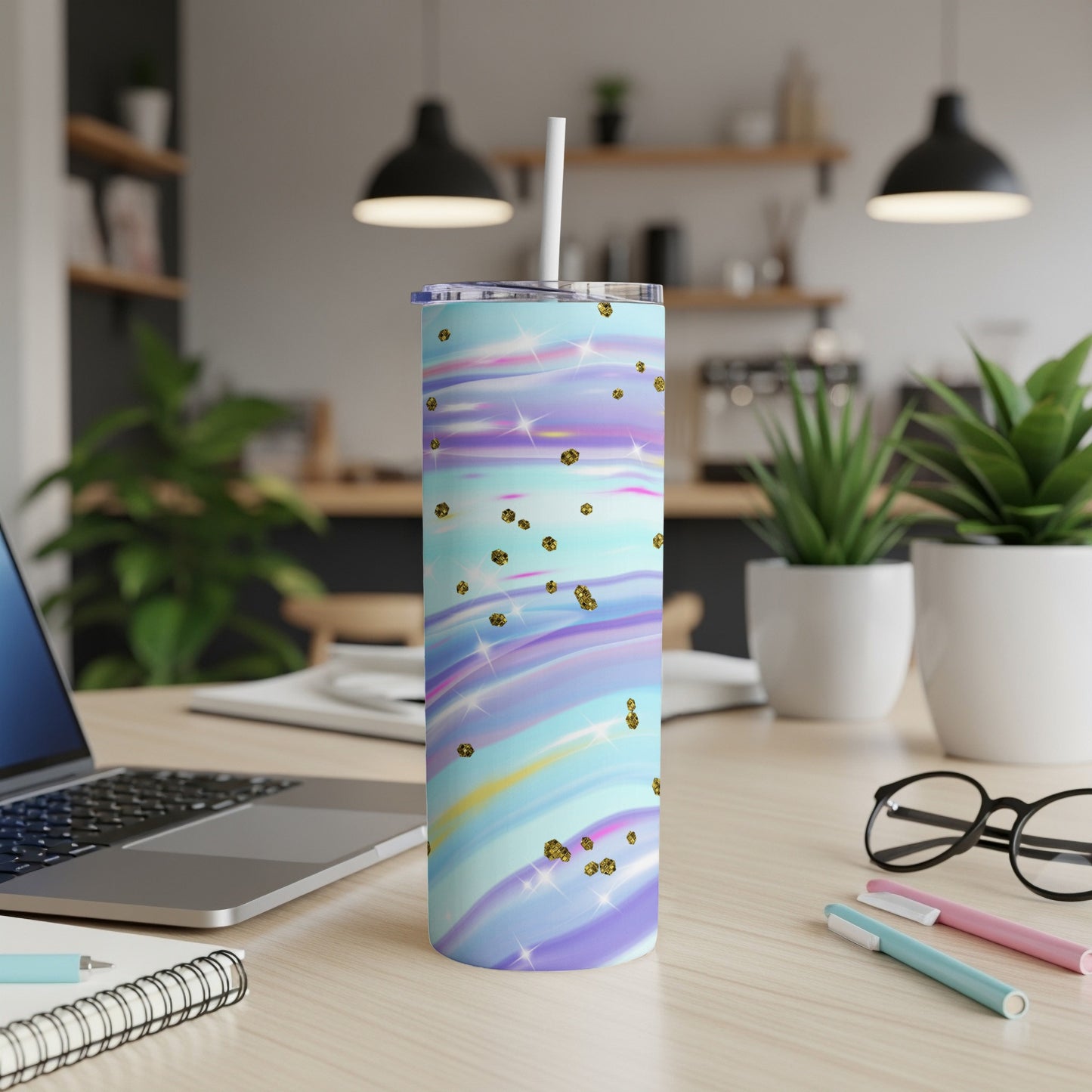 Tumbler with swirling pastel colors and gold glitter specks on a desk.