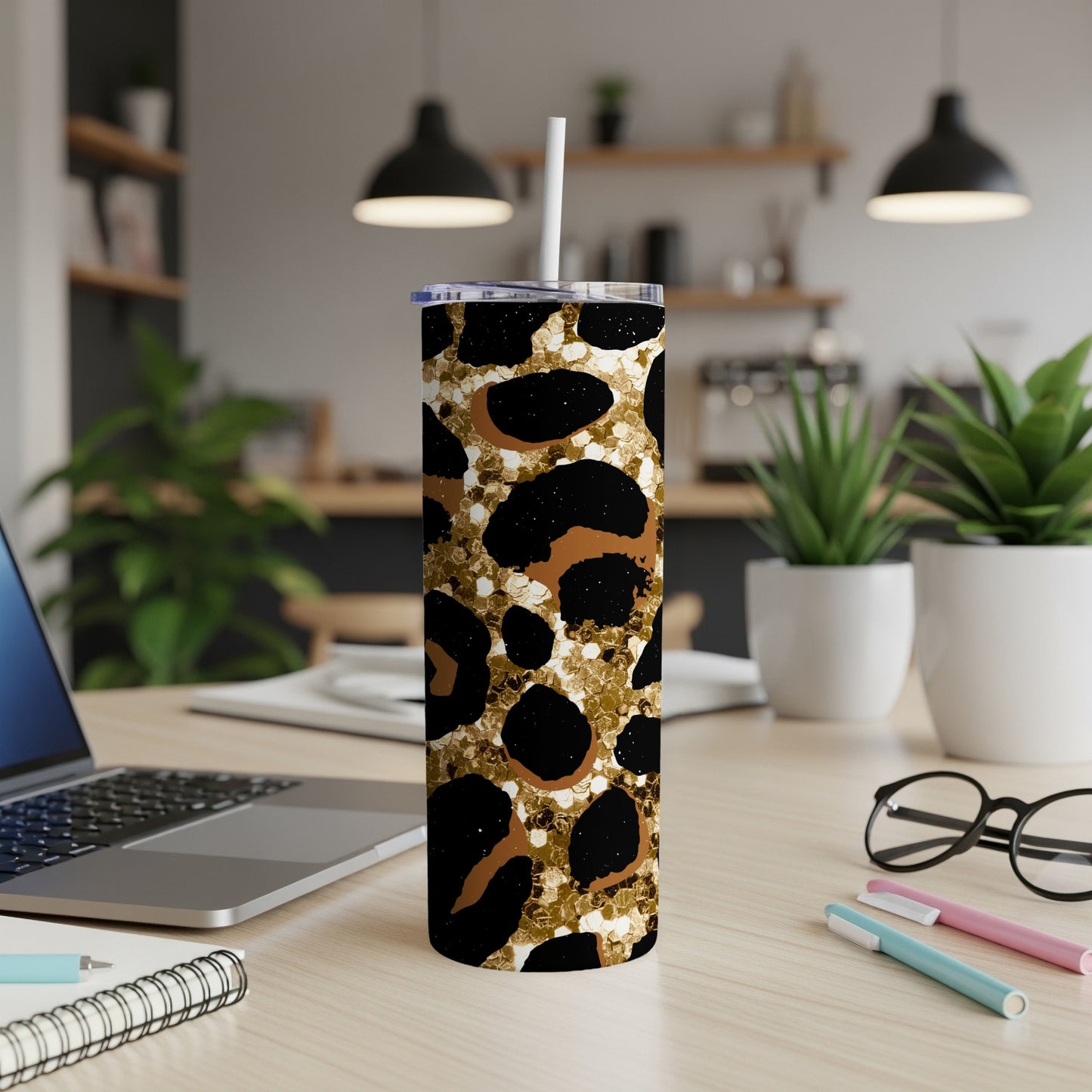 Leopard print glitter tumbler with straw on a desk.
