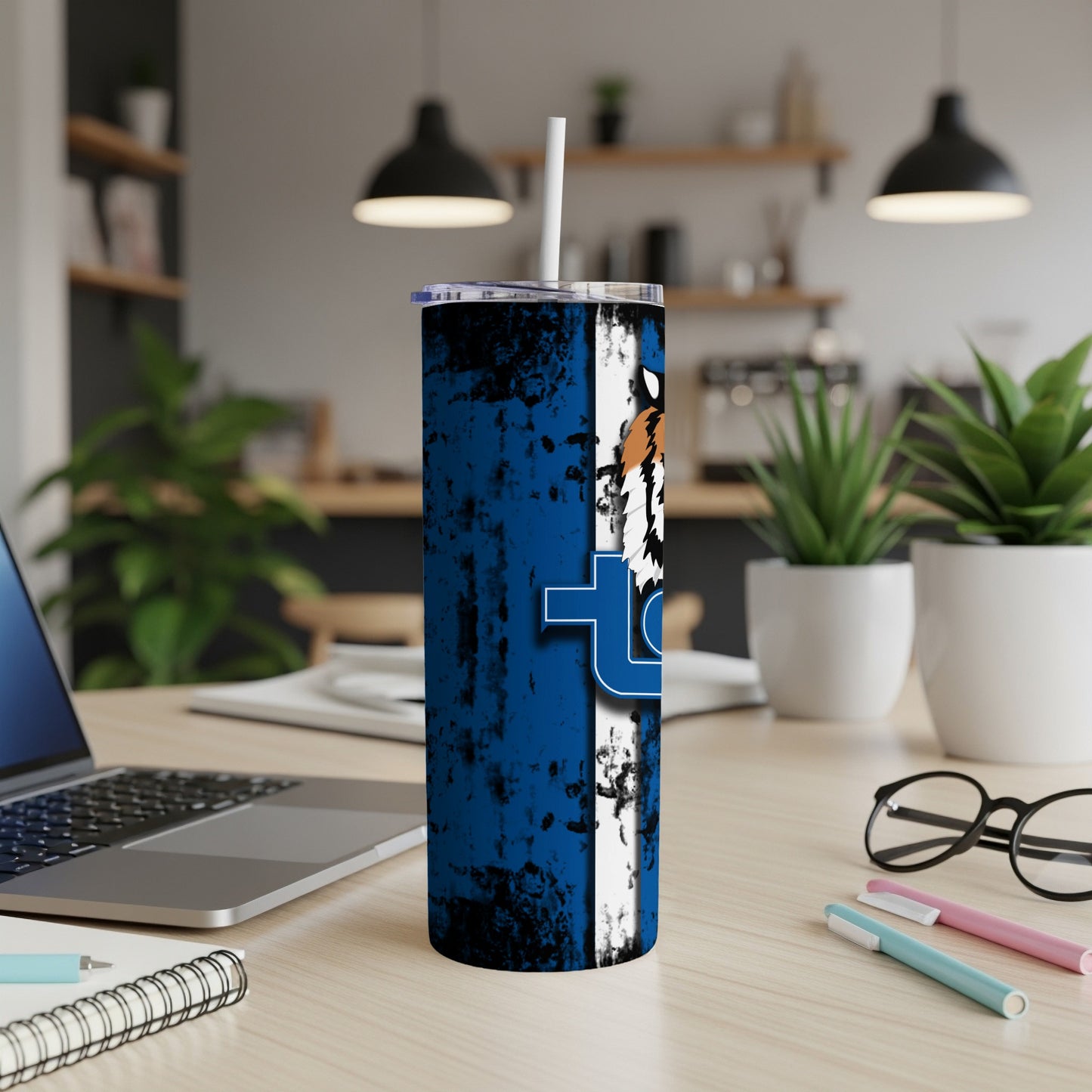 Blue tumbler with tiger print and white 't' logo on a desk.