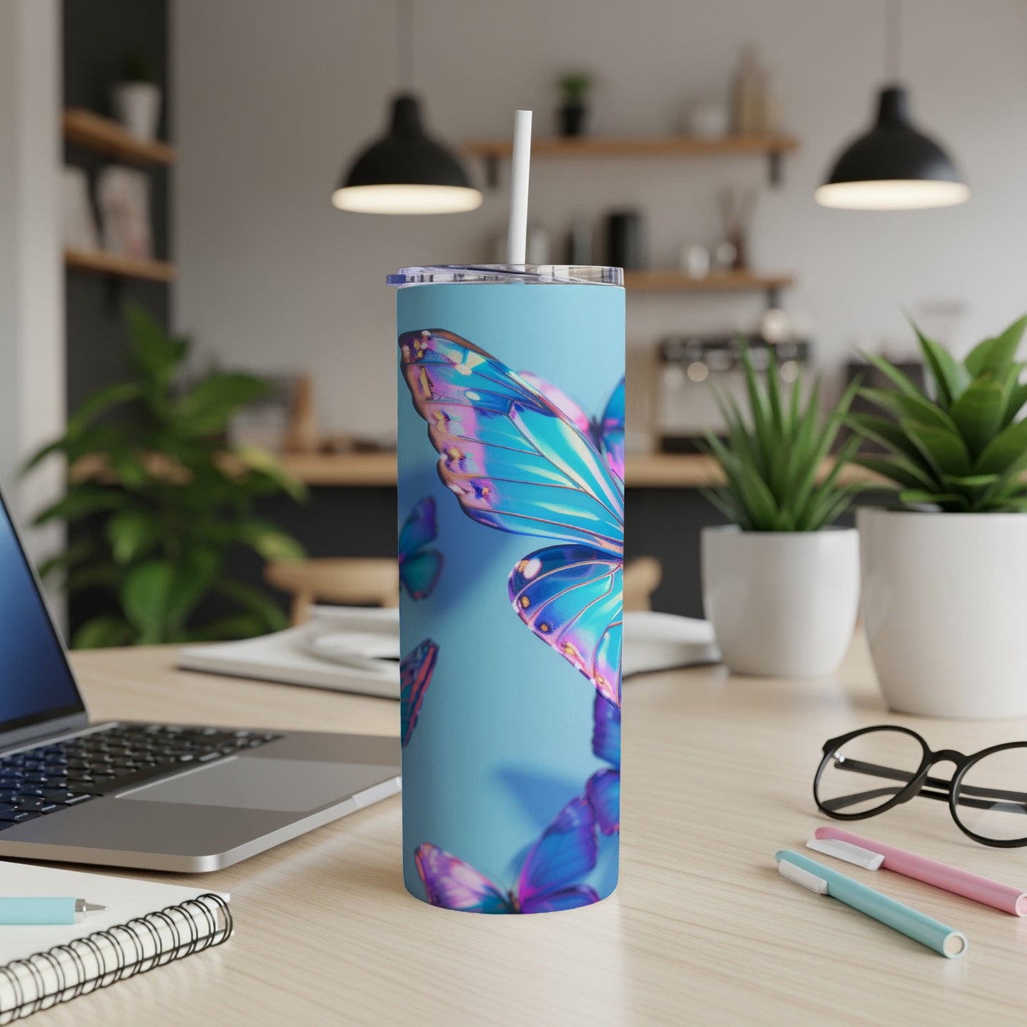 Blue tumbler with iridescent butterfly design on a desk.