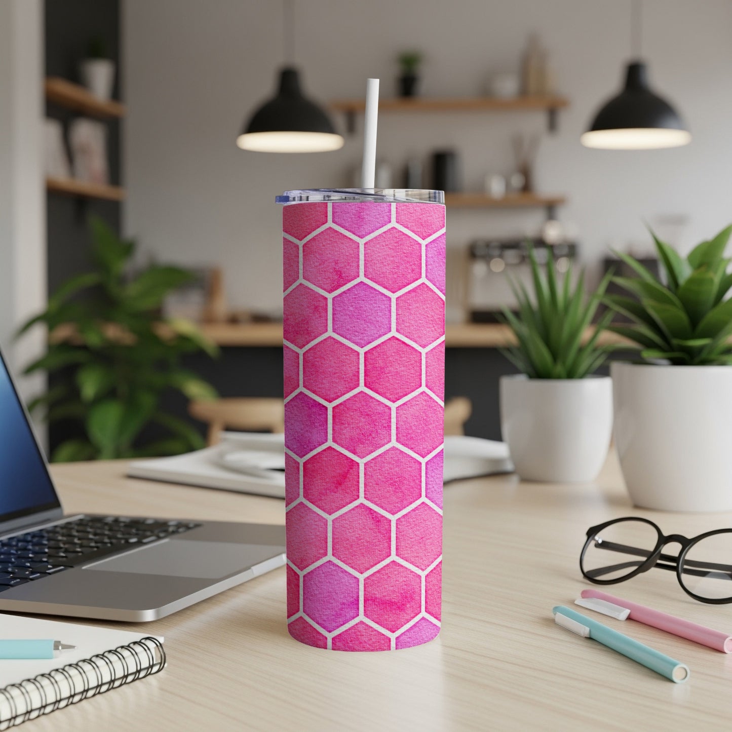 Pink hexagon pattern tumbler with a white straw on a desk.