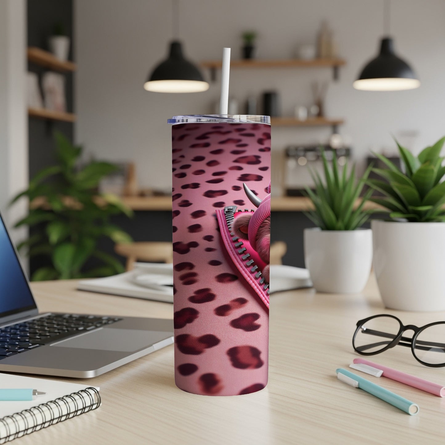 Pink leopard print tumbler with a zipper detail and straw on a desk.