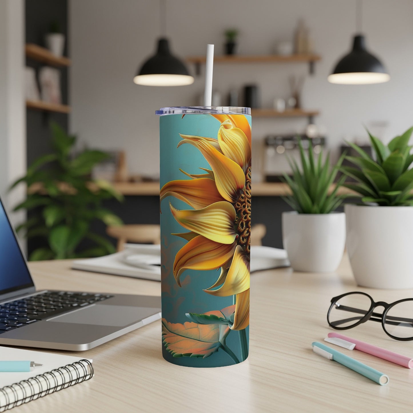 Teal tumbler with a large sunflower design and a straw.