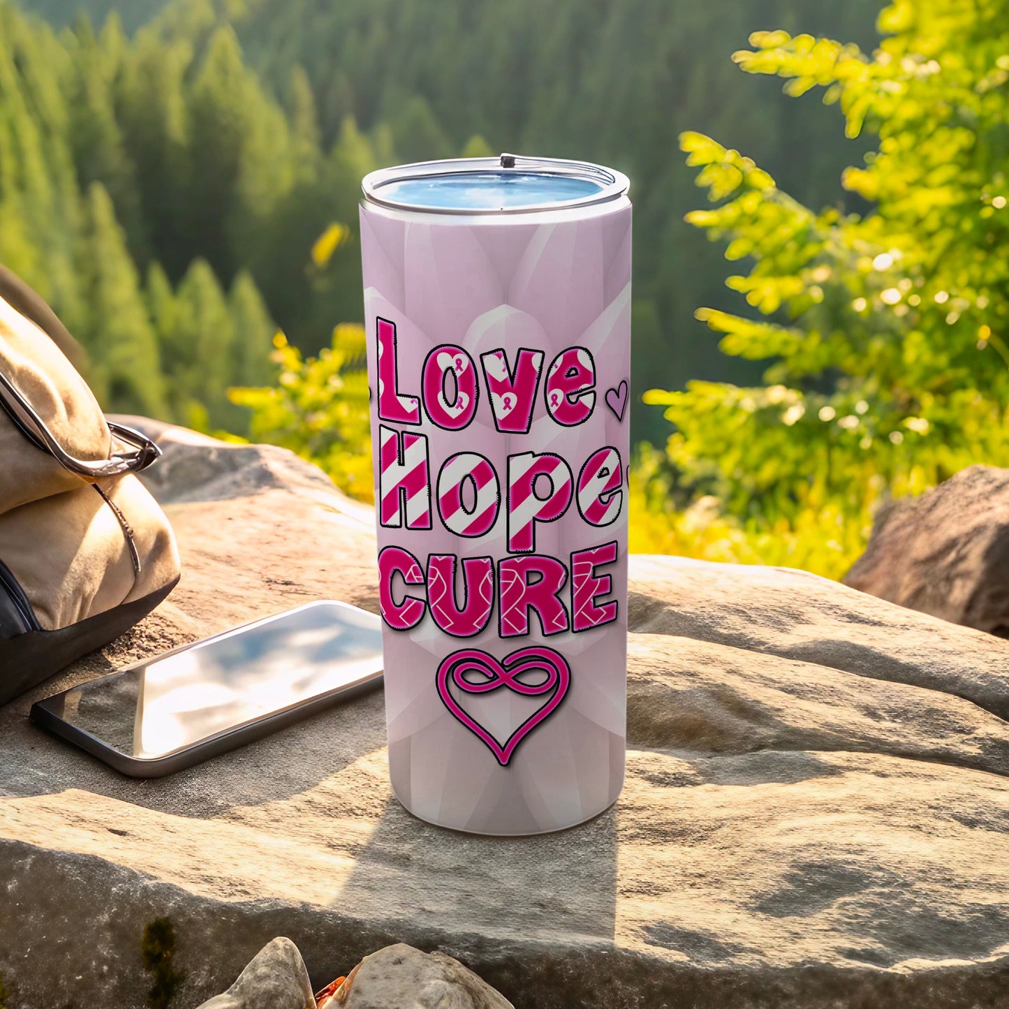 Pink tumbler with "Love Hope Cure" and heart pattern on a rock.