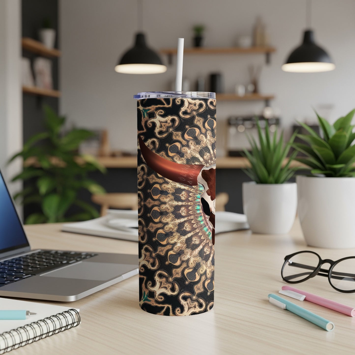 Gold and black patterned tumbler with skull and feather details.
