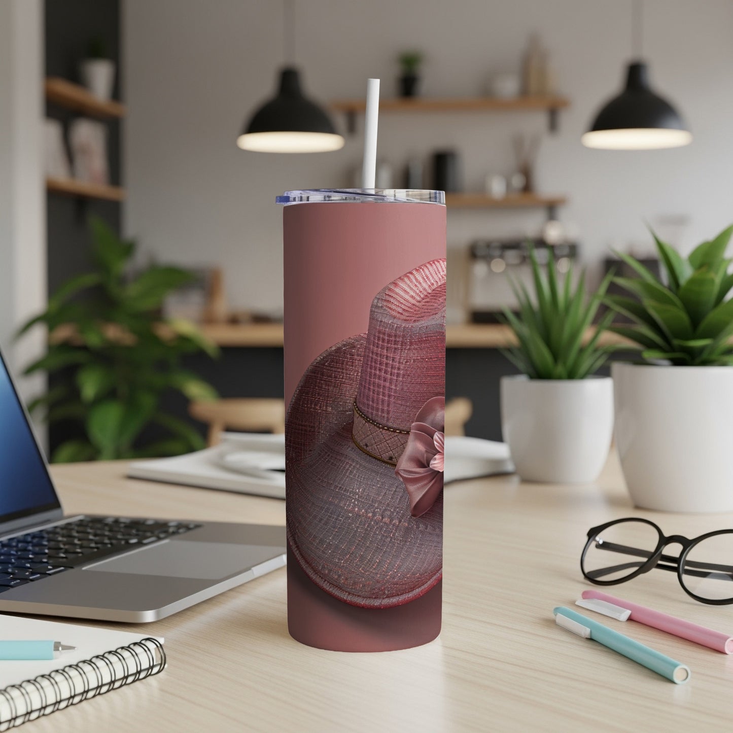 Rose gold tumbler with woven pattern and pink bow, on a desk.